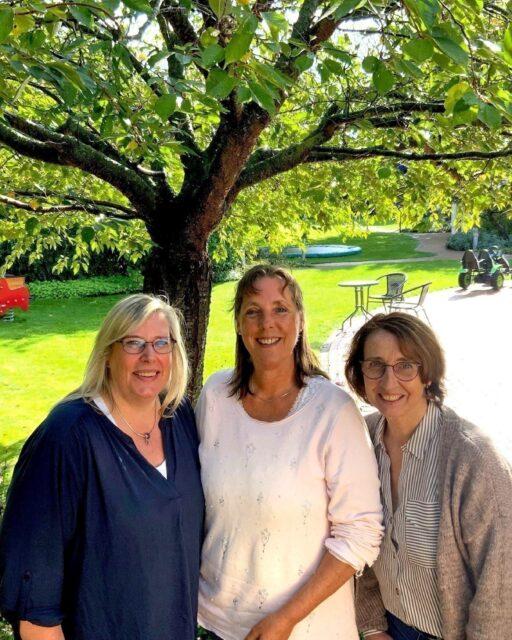 Drei ältere Löwenherz-Pflegerinnen stehen unter einem Baum im Garten vom Kinderhospiz