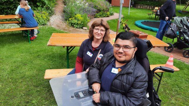Ein junger Mann im Rollstuhl, Wian, sitzt mit seiner persönlichen Assistenz im Löwenherz-Garten