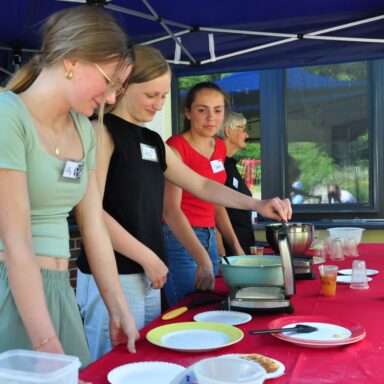 Drei Schülerinnen und eine Löwenherz-Ehrenamtliche backen Waffeln.