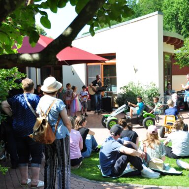 Viele Menschen auf einer Wiese des Kinderhospiz hören einem Kinderchor zu.