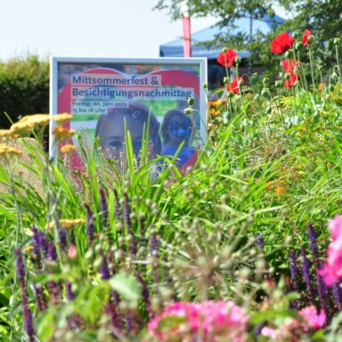 Das Plakat Mittsommerfest im Kinderhospiz-Garten mit vielen bunten Blumen.