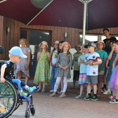 Ein kleiner Junge im Rollstuhl hört einem Kinderchor zu.