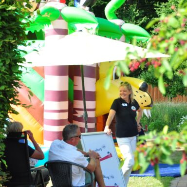 Eine Löwenherz-Ehrenamtliche steht vor einer Hüpfburg im Löwenherz-Garten.