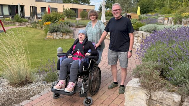 Die Eltern Britta und Gerd mit ihrer im Rollstuhl sitzenden Tochter Lena im Garten des Kinderhospiz Löwenherz