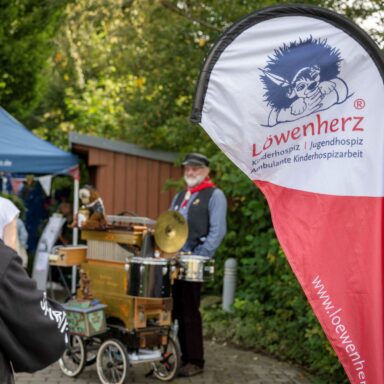Eine Löwenherz-Beachflag, im Hintergrund ein Leierkastenmann.