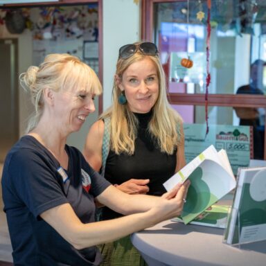 Zwei Mitarbeitende der Löwenherz-Akademie blättern im neuen Programmheft.