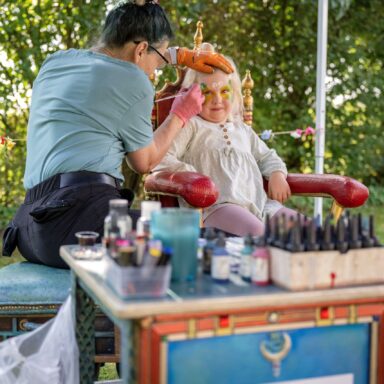 Ein kleines Mädchen wird beim Kinderschminken im Gesicht bemalt.