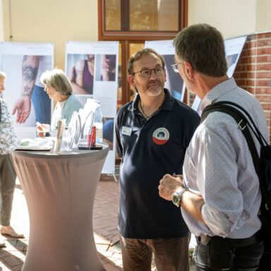 Menschen im Gespräch vor Motiven der Wanderausstellung "Unter die Haut"