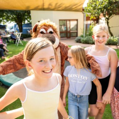 Vier Mädchen posieren mit Maskottchen Maximilian Löwenherz