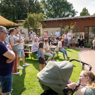 Menschen stehen im Löwenherz-Garten und schauen in Richtung eines Kinderchores.