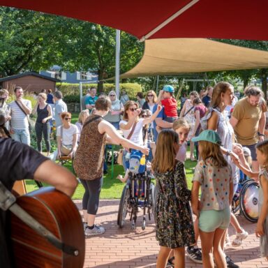 Vielen junge und alte Menschen tanzen bei Sonne im Garten vom Kinderhospiz Löwenherz.