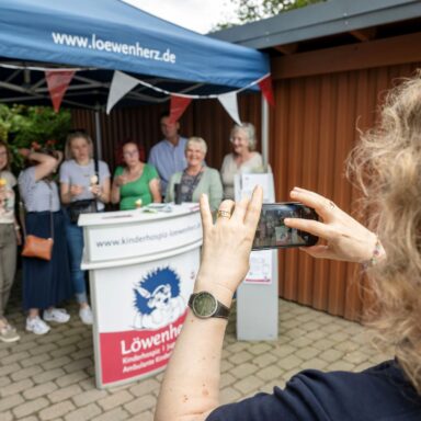 Ein Mensch fotografiert eine Menschengruppe mit dem Handy