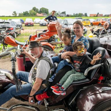 Eine Mutter sitzt mit zwei Kindern auf einem Trike