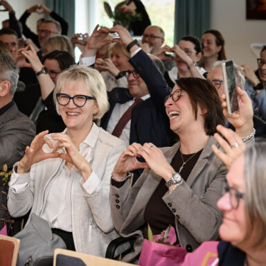 Viele Menschen im Treffpunkt Löwenherz bilden mit ihren Fingern ein Herz nach.