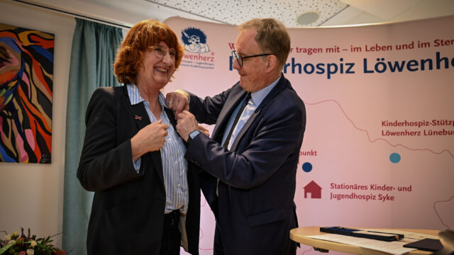 Landrat Volker Meyer steckt Löwenherz-Pionierin Gaby Letzing das Bundesverdienstkreuz an den Blazer